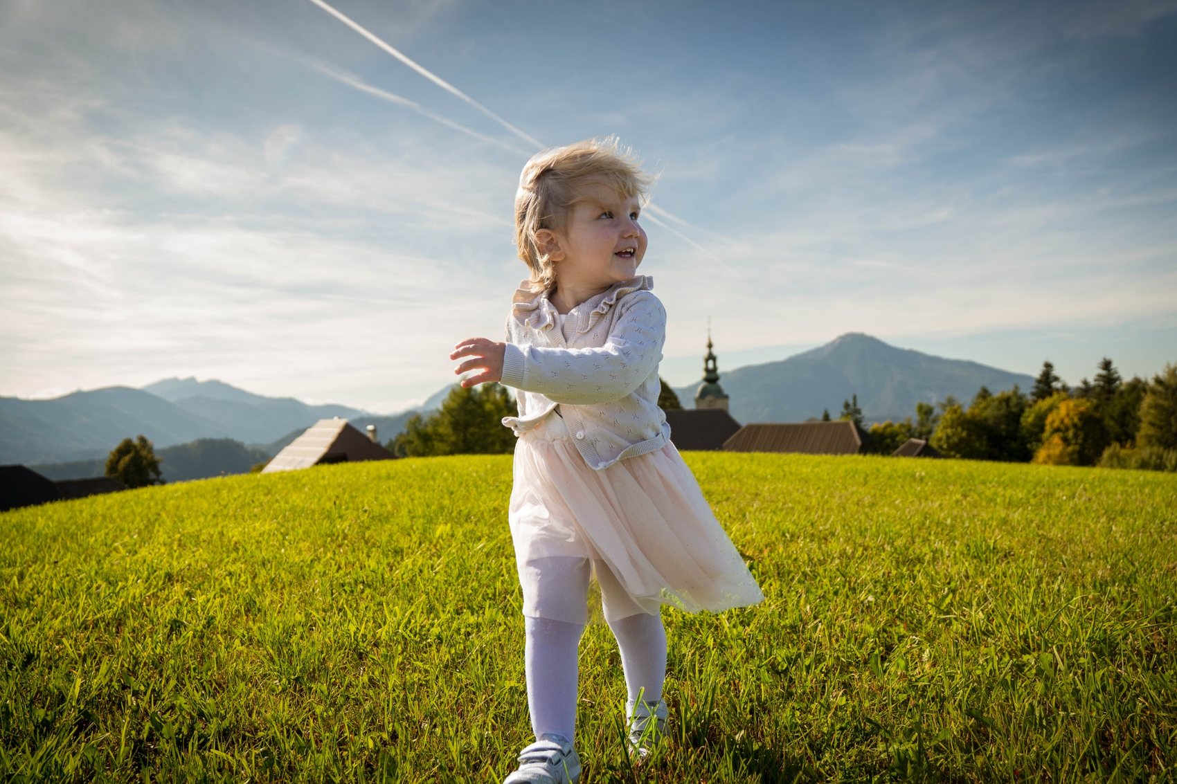 Otroški portret na travniku z gorskim ozadjem